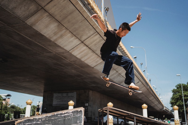 A man performing a skateboard trick under a bridge.