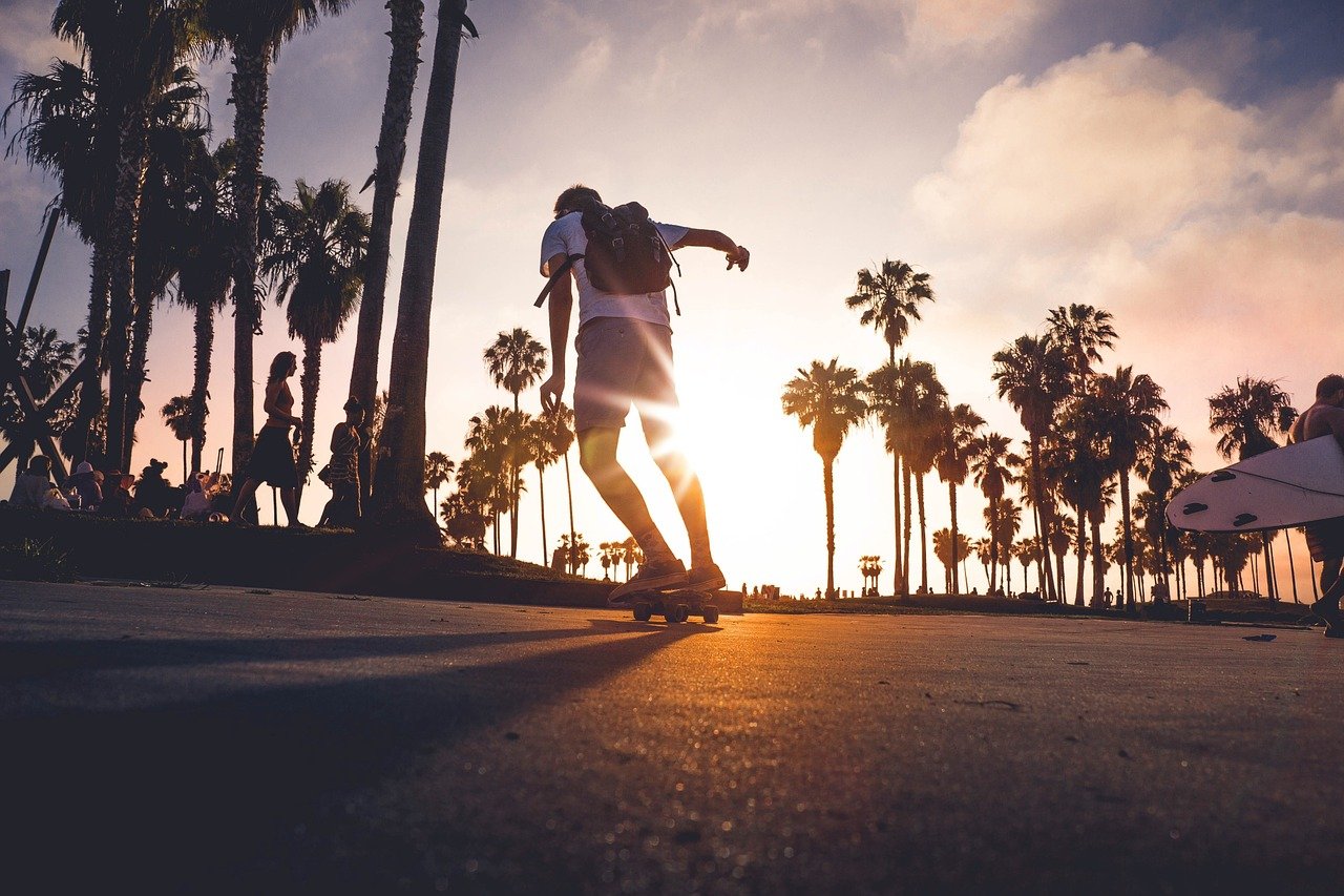 A man is skateboarding in front of palm trees at sunset.