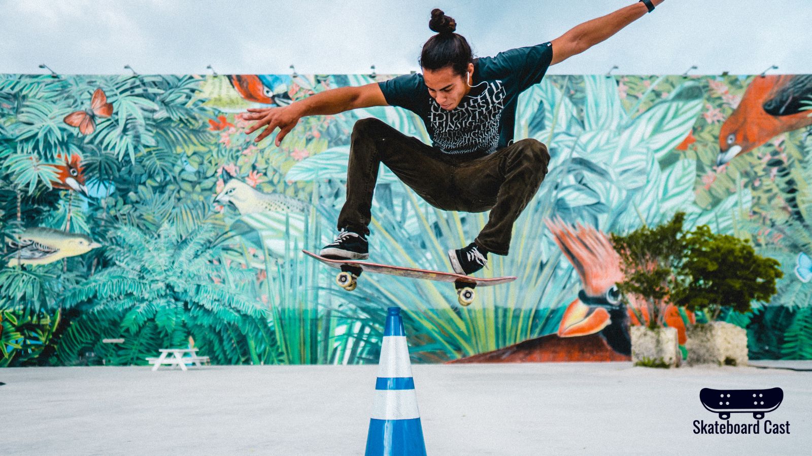 A skateboarder performing a trick in front of a mural.